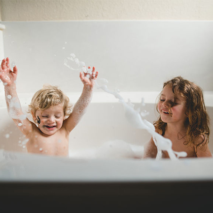Twp young children splashing around in a bathtub